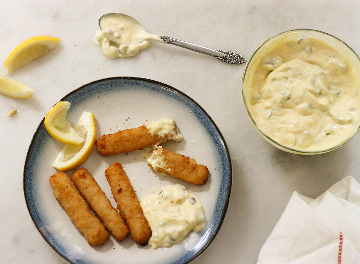 Salsa tartara con bastoncini di pesce e spicchi di limone su un piatto